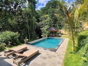 a swimming pool with two chairs and a gazebo at Mambul garden private villa in Ubud