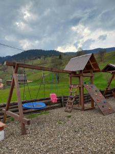 a wooden playground with a slide and a swing at У Ґазди in Synevyrsʼka Polyana
