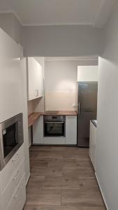 cocina con armarios blancos y nevera de acero inoxidable en Seaside Apartment, en Gdansk