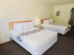 2 camas en una habitación de hotel con paredes blancas en Hotel 191 - Moab en Moab