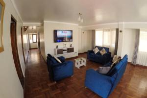 Il comprend un salon doté de canapés bleus et d'une télévision à écran plat. dans l'établissement Centric & cozy apartment with Garage, à Cusco