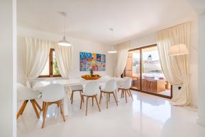 a white dining room with a white table and chairs at Villa Nena in Kakma