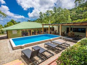 ein Schwimmbad mit Stühlen und ein Haus in der Unterkunft Hacienda La Huerta, Puerto Plata in San Felipe de Puerto Plata