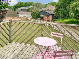 a pink table and two chairs on a wooden deck at Nightingales in Hollesley