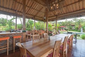 une salle à manger avec une grande table et des chaises en bois dans l'établissement Bali Sawah Indah, à Ubud