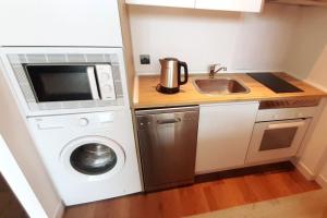 a small kitchen with a washing machine and a microwave at Loft para soñar y explorar Madrid entero para tí! in Madrid