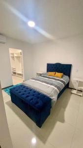 a bedroom with a blue bed in a white room at Platinum II Equipetrol frente Ventura Mall Super Lujo Hermosas Vistas in Santa Cruz de la Sierra