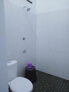 een badkamer met een wit toilet en een paarse kruk bij Griya PAS Pangandaran in Pangandaran