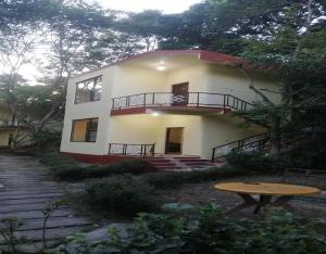 ein großes weißes Haus mit einem Tisch davor in der Unterkunft Nalgarh Retreat - JUNGLE RESORT by StayApart in Uttar Simlabari