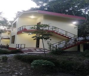 a white house with a staircase in front of it at Nalgarh Retreat - JUNGLE RESORT by StayApart in Uttar Simlabari