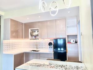 a kitchen with white cabinets and a black refrigerator at Renai Homestay Ladang Tanjung Kuala Terengganu with POOL in Kuala Terengganu