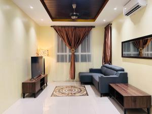 a living room with a blue couch and a tv at Renai Homestay Ladang Tanjung Kuala Terengganu with POOL in Kuala Terengganu