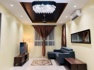 a living room with a blue couch and a chandelier at Renai Homestay Ladang Tanjung Kuala Terengganu with POOL in Kuala Terengganu +8 photos