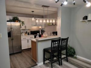 a kitchen with a stainless steel refrigerator and two chairs at Lovely green townhouse in Frederick