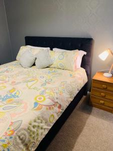 a bed with two pillows and a table with a lamp at Quiet home with modern touch in Dunedin