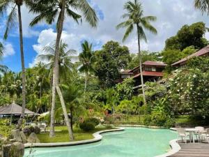 a pool in front of a resort with palm trees at Private Tropical 3 Bedroom Villa - Nongsa Village Batam in Telukmataikan