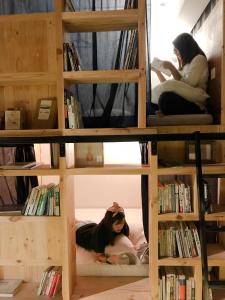dos mujeres sentadas en camas en un estante de libros en Route Five Hostel Dorm Kuala Selangor, en Kuala Selangor