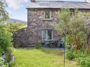 a stone cottage with a table and chairs in the yard at Ty Dyfnant Cottage in Penmachno