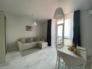 uma sala de estar com uma mesa e um sofá em Apartments LUNA em Kobuleti