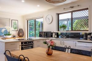 a kitchen with a table with a vase of flowers on it at Teak Street Retreat - Ultimate Comfort Steps to Maleny Main Street in Maleny