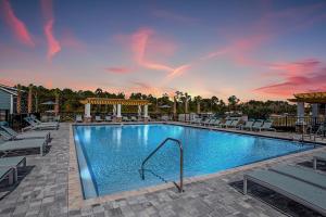 a swimming pool at a resort with chairs and a sunset at "Two Bella" Luxury Apt - POOL - 4 Mi to Beach in Daytona Beach