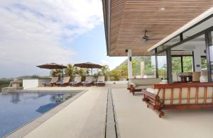 una piscina con sillas y sombrillas en una casa en Kulraya Villas - Luxury Serviced Pool Villas (A), en Ko Lanta