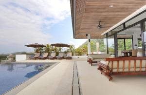 a swimming pool with chairs and umbrellas on a house at Kulraya Villas - Luxury Serviced Pool Villas (A) in Ko Lanta