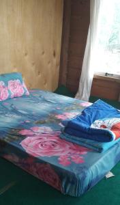 a bed with a blue blanket with flowers on it at Purabarang Homestay in Rantepao