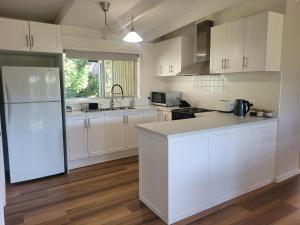 a kitchen with white cabinets and a white refrigerator at Healesville Schofield Cottage in Healesville