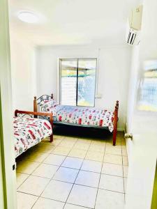 a room with two beds and a window at Grabber- Three bedroom charm in Alice Springs in Alice Springs