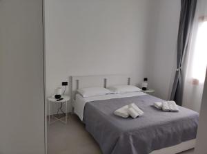 een witte slaapkamer met 2 witte handdoeken op een bed bij Villa Rita in Fontane Bianche