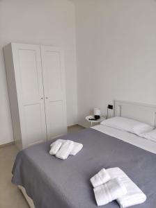 een witte slaapkamer met 2 handdoeken op een bed bij Villa Rita in Fontane Bianche