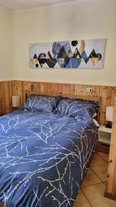 a bed with a blue comforter and pillows at Appartamento Val di Luce Relax Cristallo in Abetone