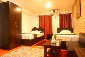 a hotel room with two beds and a couch at Hotel Malla Inn in Bhaktapur