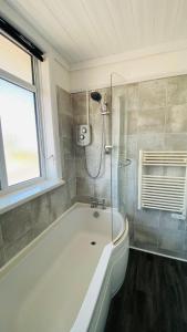 a bathroom with a tub and a shower with a window at Family Marine Apartment with Sea View in Dawlish