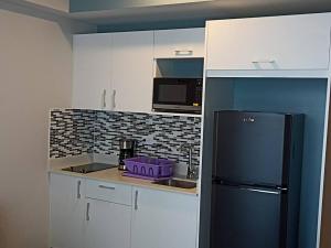 a kitchen with white cabinets and a black refrigerator at Prime city loft with skyline views and a dedicated workspace in San José
