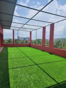 a large room with green grass and a roof at Gulzar 2BHK Service Apartment, kannur in Kannur