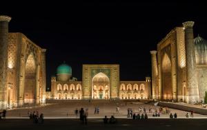 un grande edificio con gente che cammina intorno di notte di Aisha Registan a Samarkand