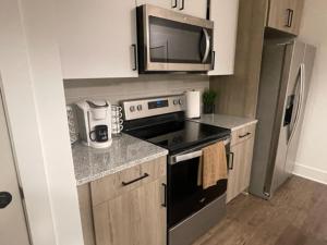 a small kitchen with a stove and a microwave at Indulge in a luxury apartment in Lawrenceville