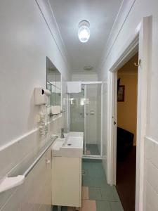a white bathroom with a sink and a shower at The North Shore Hotel in Sydney
