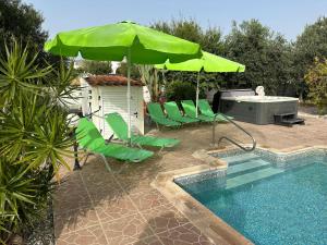 een zwembad met groene stoelen en een tafel en een parasol bij Villa Coralia Gardens 1km From Coral Bay Beach in Coral Bay