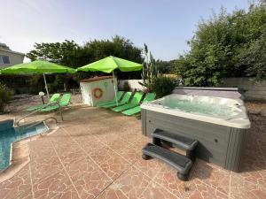 a hot tub with chairs and umbrellas next to a pool at Villa Coralia Gardens 1km From Coral Bay Beach in Coral Bay