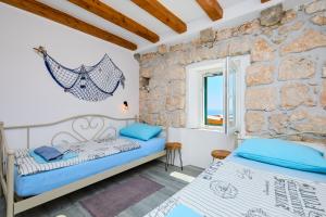 a bedroom with two beds and a stone wall at Stone House Biskup in Babino Polje
