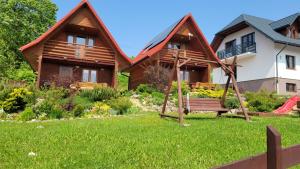 een houten huis met een schommel in de tuin bij domki nad jeziorem in Wołkowyja