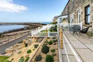 a house with a balcony with a view of the ocean at Old Coastguard Cottages in Amble