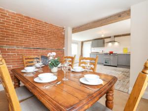 a dining room with a wooden table and a brick wall at South Grange Cottage in Saxmundham