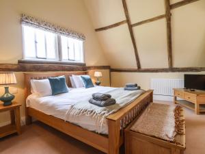 a bedroom with a large bed and a tv at South Grange Cottage in Saxmundham