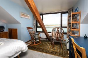 a bedroom with a bed and two chairs and a window at Old Coastguard Cottages in Amble