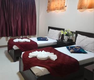 Habitación con 2 camas y sábanas rojas y blancas. en HilFrans Lodge, en Vigan
