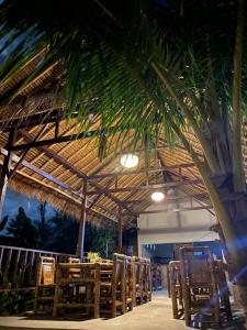 um restaurante com cadeiras e um telhado de palha em Cewin's Homestay em Kuta